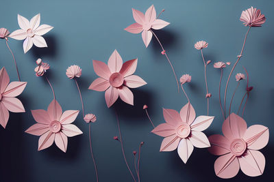 Pink paper cut flowers on blue background. abstract floral pattern