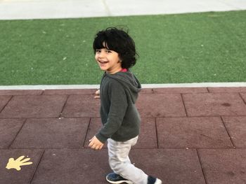 Portrait of cheerful boy walking on footpath