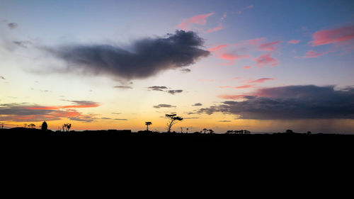 Scenic view of dramatic sky over silhouette landscape during sunset