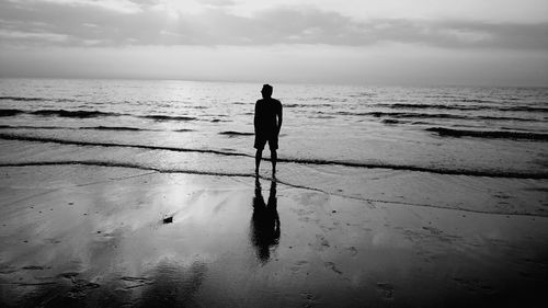 Silhouette man standing on shore at beach