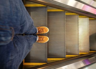 Low section of man standing on escalator