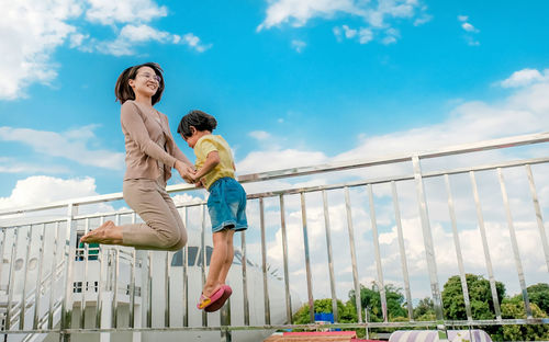 Woman with arms raised against sky