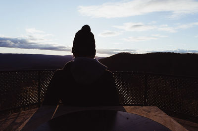 Rear view of man sitting at table against sky