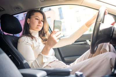 Midsection of woman using mobile phone while sitting in car