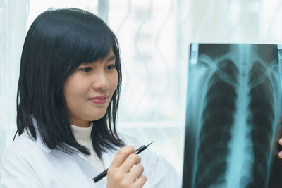 Smiling female doctor examining x-ray image in hospital