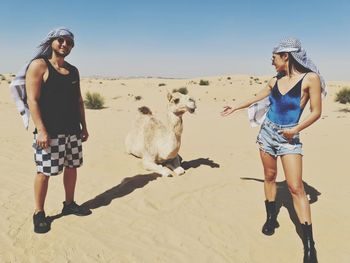 Young couple playing with camel on the desert