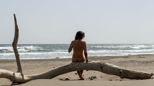 Rear view of shirtless man looking at sea against sky