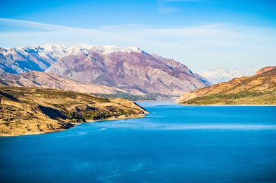 Scenic view of sea and mountains against blue sky