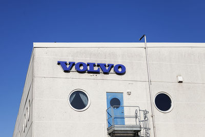 Low angle view of text on building against clear blue sky