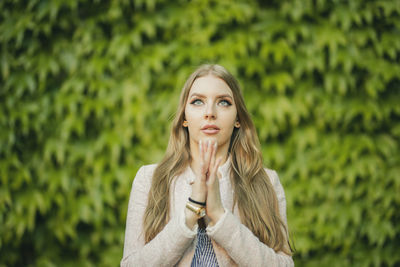 Beautiful woman holding crystal praying against plants