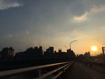 City street and buildings against sky during sunset