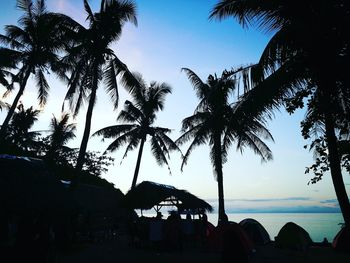 Silhouette palm trees on beach against sky