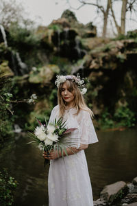 Portrait of a smiling young woman standing against plants