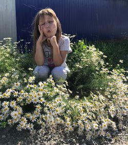 Cute girl crouching amidst flowering plants