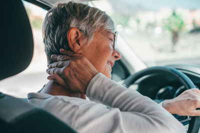 Senior woman having neck ache in car