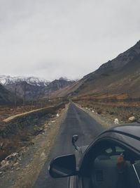Road amidst mountains seen through car windshield