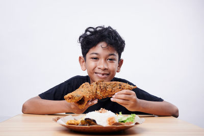 Portrait of young woman eating food against white background