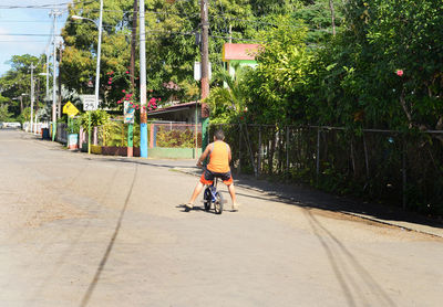 Rear view of boy riding bicycle on street