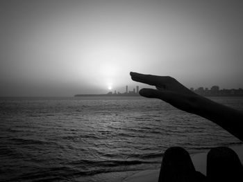 Silhouette person on sea against sky during sunset