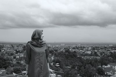 Rear view of woman standing by cityscape against sky