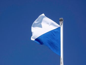 Low angle view of flag against blue sky