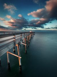 Pier on sea against sky at sunset