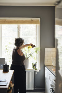 Woman with disability spraying water on plants at home