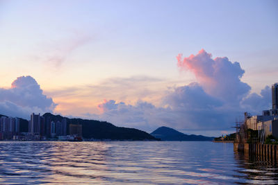 Buildings by sea against sky during sunrise