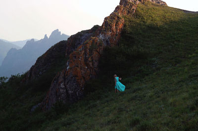 Rear view of woman in turquoise dress while walking on mountain