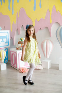 Portrait of cute girl standing against wall