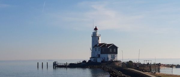 Lighthouse by sea against sky