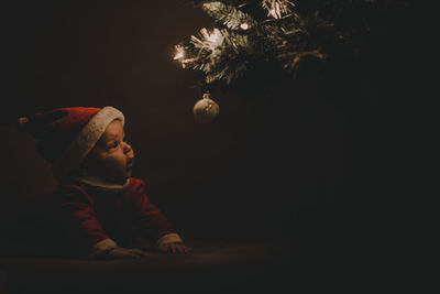 Baby girl looking at illuminated christmas tree at night