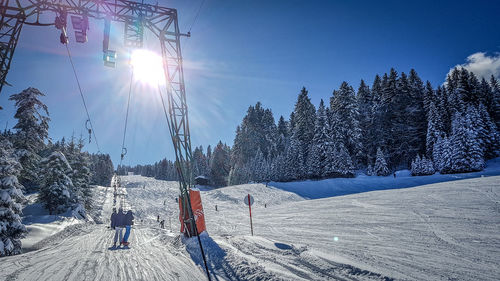 People skiing on snow covered landscape against sky