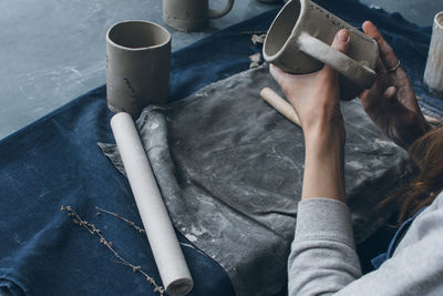 Cropped hands of woman making mug on table