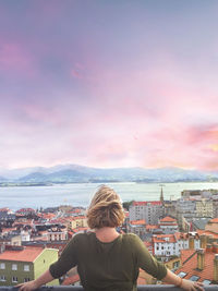 Rear view of woman looking at cityscape against sky