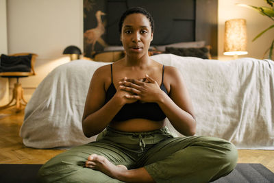 Portrait of young woman practicing breathing exercise in bedroom at home