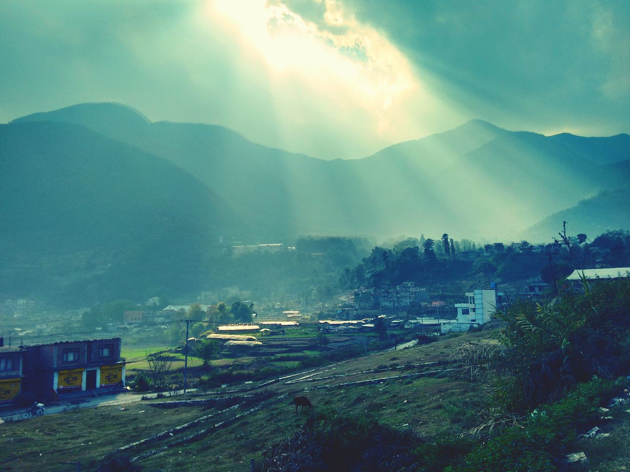 mountain, landscape, building exterior, built structure, sunbeam, architecture, mountain range, sky, sunlight, sun, house, scenics, tranquil scene, nature, tranquility, beauty in nature, high angle view, lens flare, tree, rural scene