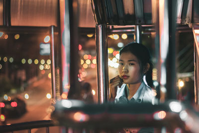 Portrait of woman looking through window at night