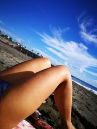 Midsection of woman relaxing on blue sea against sky