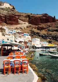 Chairs and tables by sea against clear sky