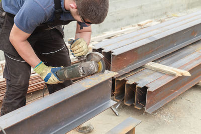 Welder cutting metal with electric saw