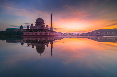 View of putra mosque by lake at sunrise