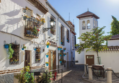 White house with flowers at its windows in oldtown of granada, spain