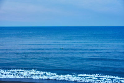 Scenic view of sea with surfer floating against sky