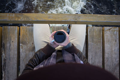 Low section of man having drink on bridge over river