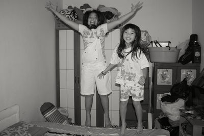 Full length portrait of happy girls on bed at home