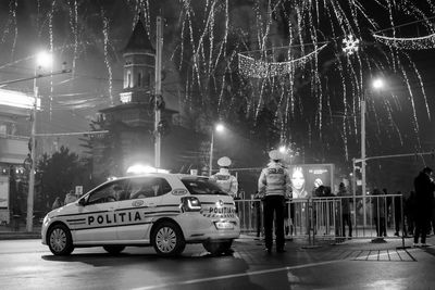 Man standing on illuminated car against sky at night