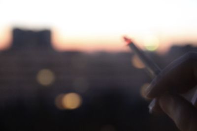 Close-up of hand holding silhouette against sky during sunset