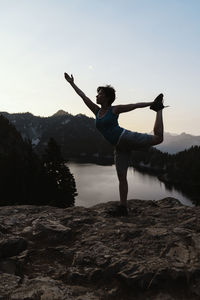 Full length of woman standing on rock at mountain during sunset