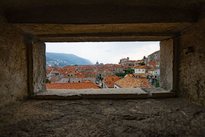 Buildings against sky seen through window